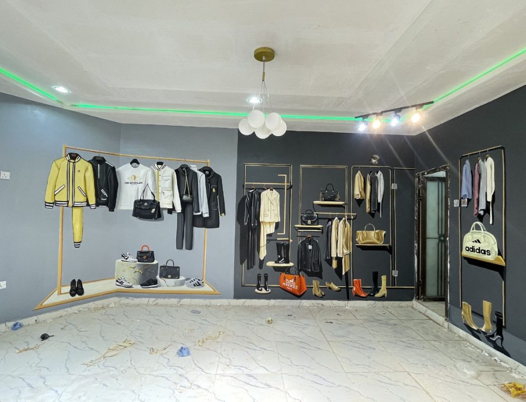 3D fashion-inspired mural by Cedar Creative Art showing realistic clothing, handbags, shoes, and accessories painted on walls to resemble a luxury boutique display.