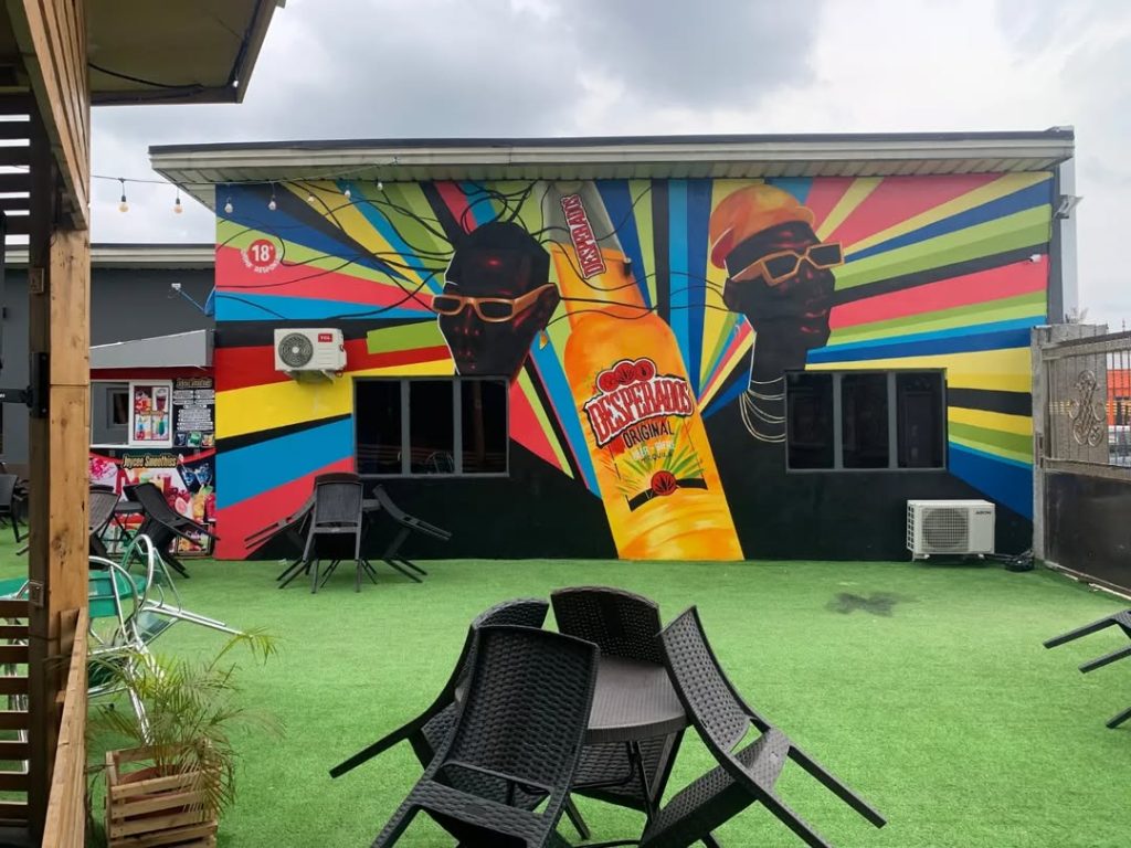 Stunning bar mural design featuring a large bottle of Desperado drink between two illustrations of Yoruba tribal faces. The color is a mix of green, orange, yellow, blue, and related colors.